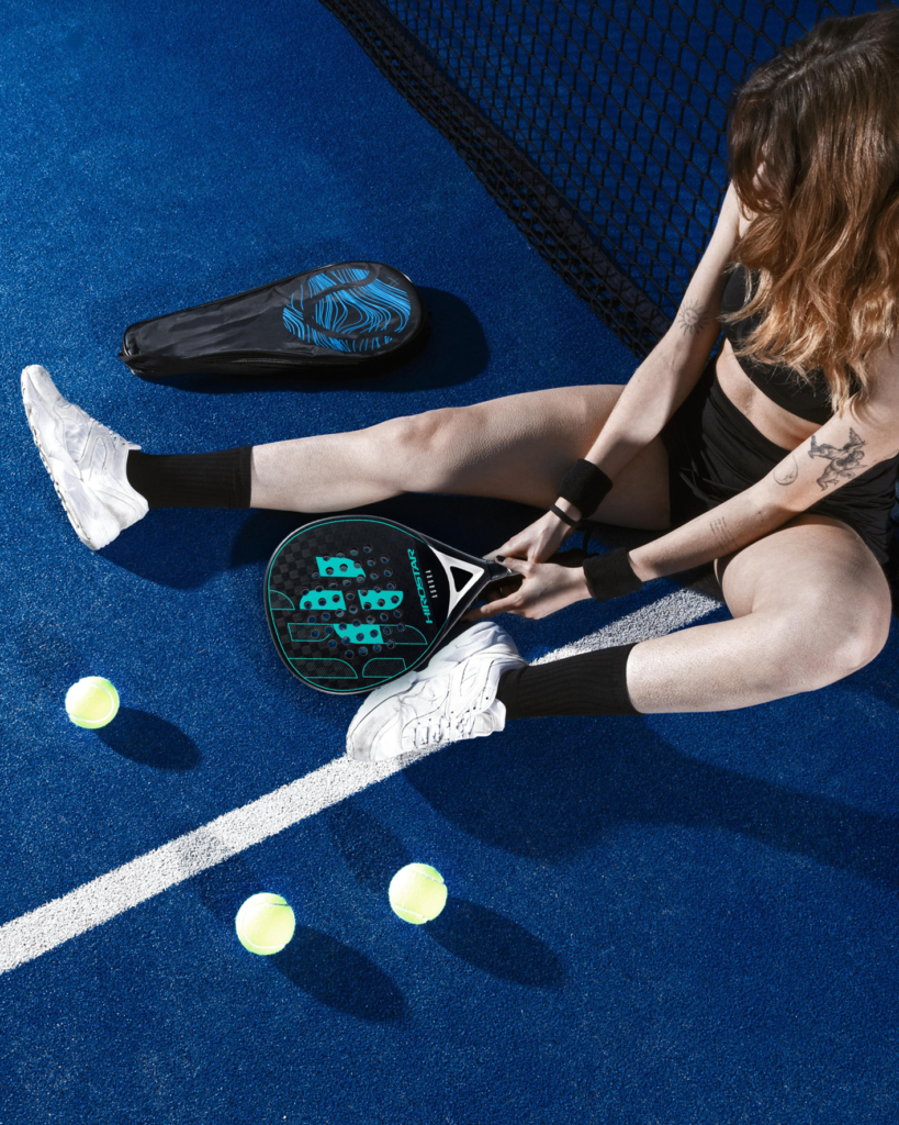 a woman sitting on a tennis court with tennis balls and racket